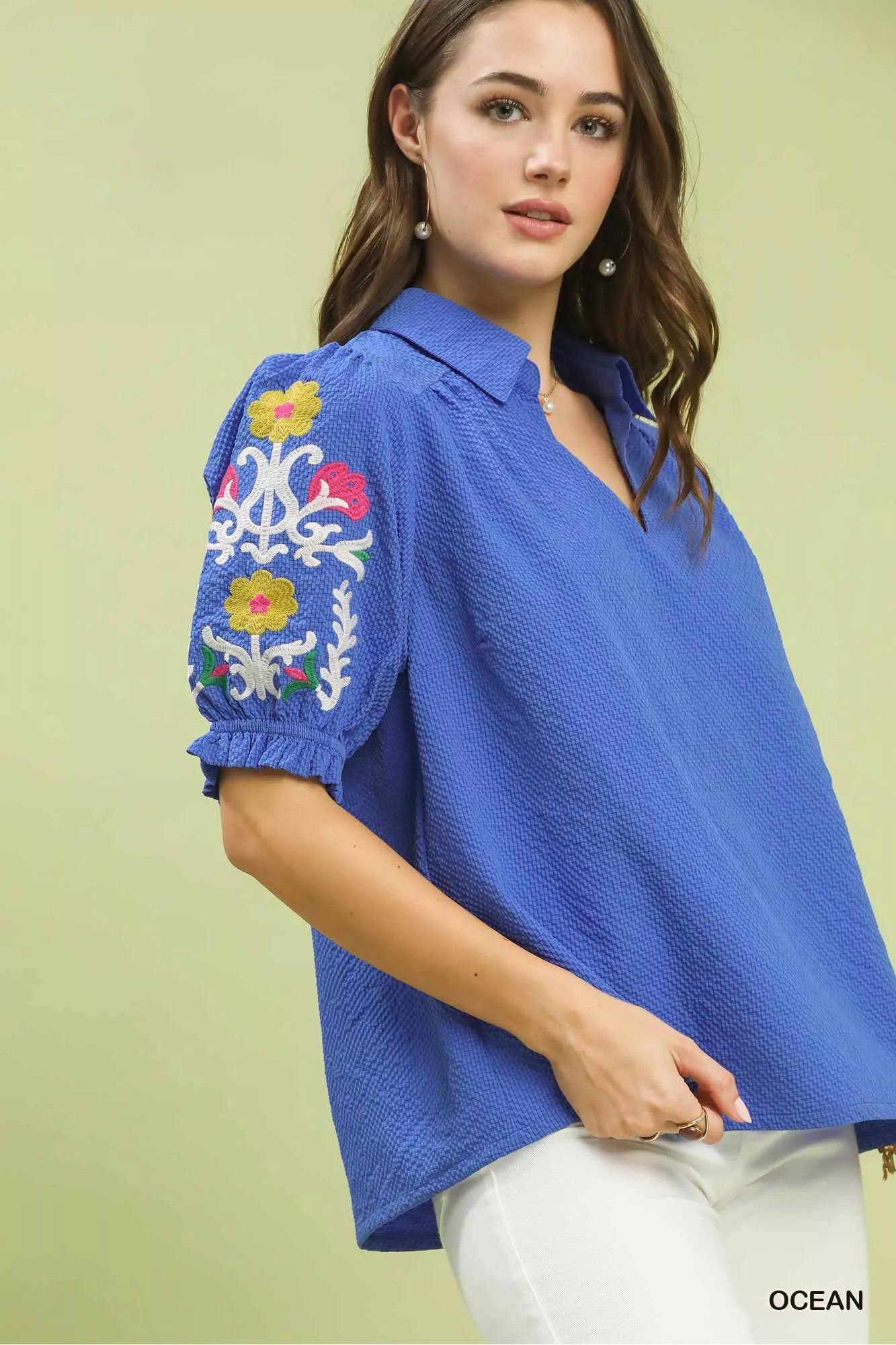 Side view of Umgee blue seersucker embroidered sleeve blouse with floral embroidery