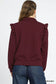 Back view of burgundy ruffled quarter-zip sweatshirt with denim jeans