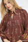 Woman wearing brown floral boho peasant blouse with tie neck, rayon nylon fabric