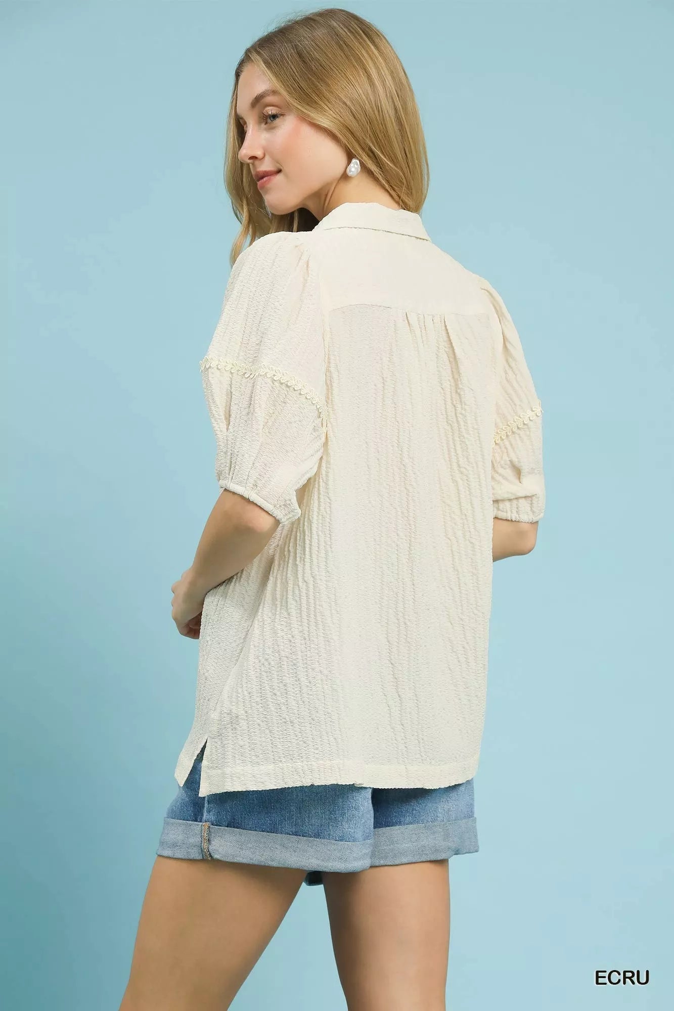 Back view of ecru textured puff sleeve blouse with denim shorts at Blueberi Boutique