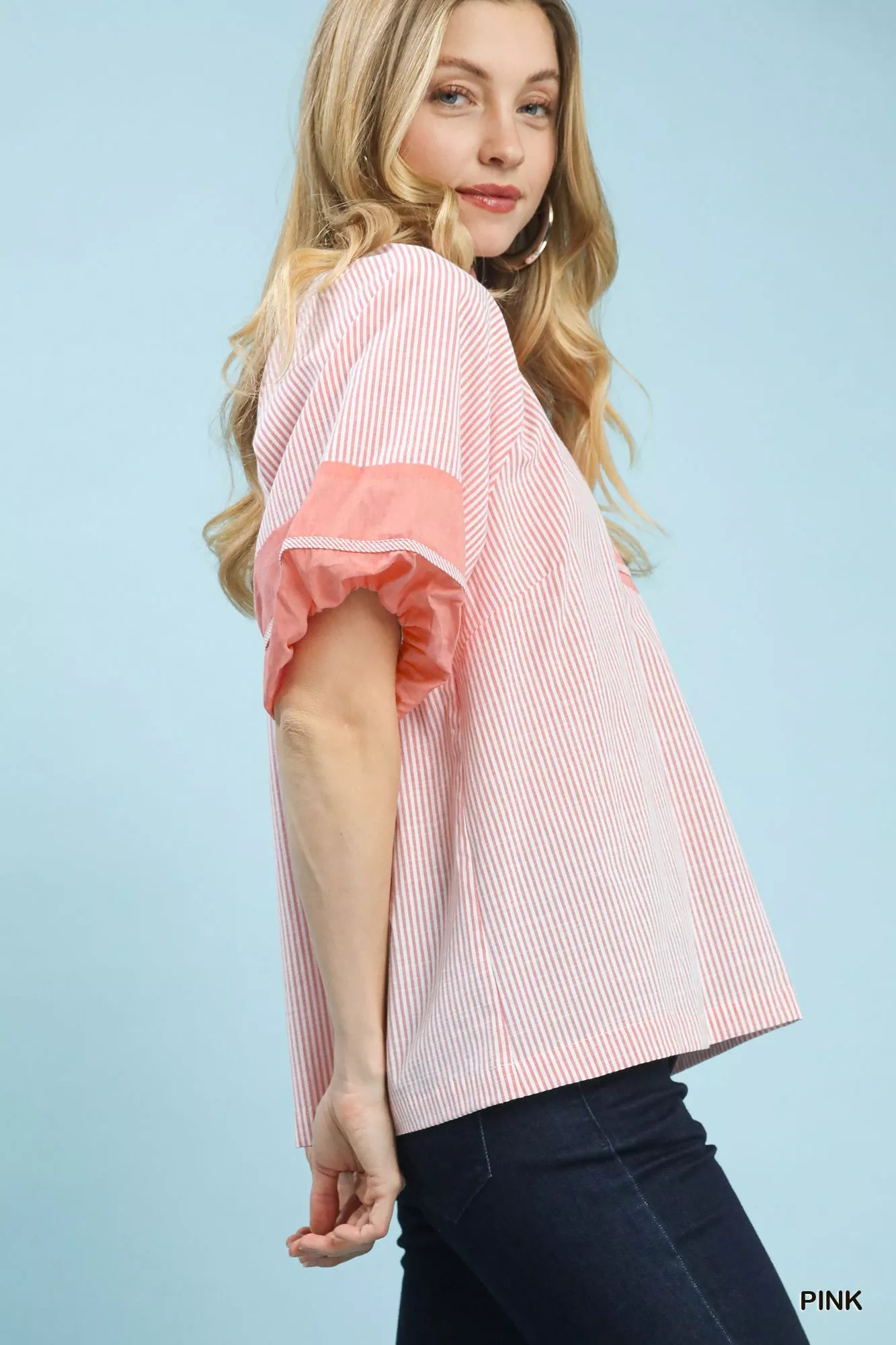Umgee pink and white striped mixed puff sleeve blouse with coral puff sleeves, model in dark jeans