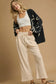 Woman wearing cream wide leg pants with white crop top and black cardigan