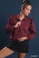 Burgundy ruffled shoulder quarter-zip sweatshirt onmodel with black skirt