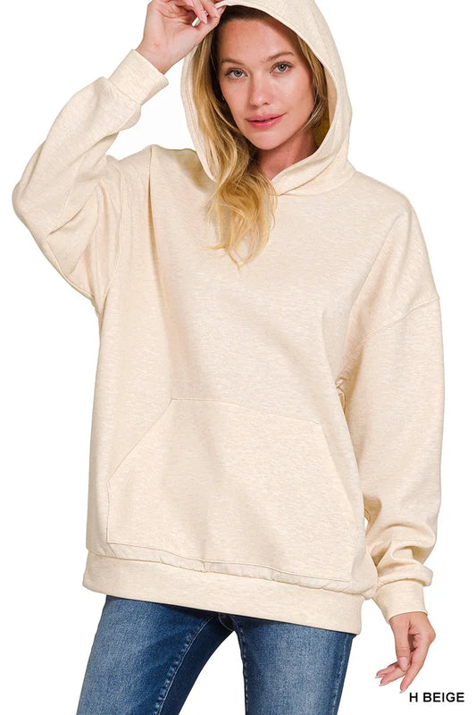 Woman wearing a beige hoodie with a plain background