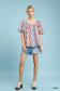 Model wearing colorful patchwork puff sleeve smocked blouse with denim shorts at Blueberi Boutique