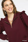 Close-up of burgundy ruffled quarter-zip sweatshirt with layered necklaces